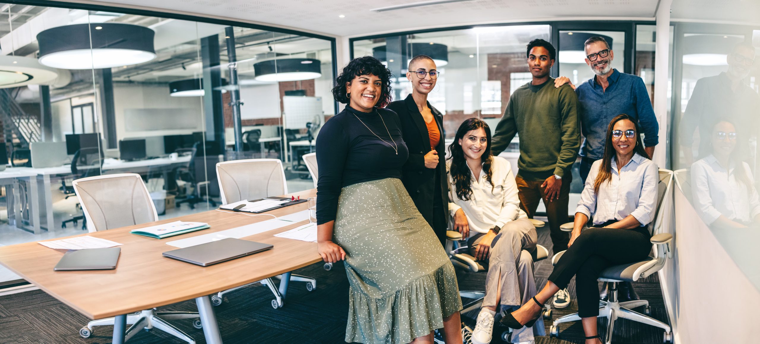 A diverse group of professionals, including men and women of various ethnicities, collaborate in a modern office space.