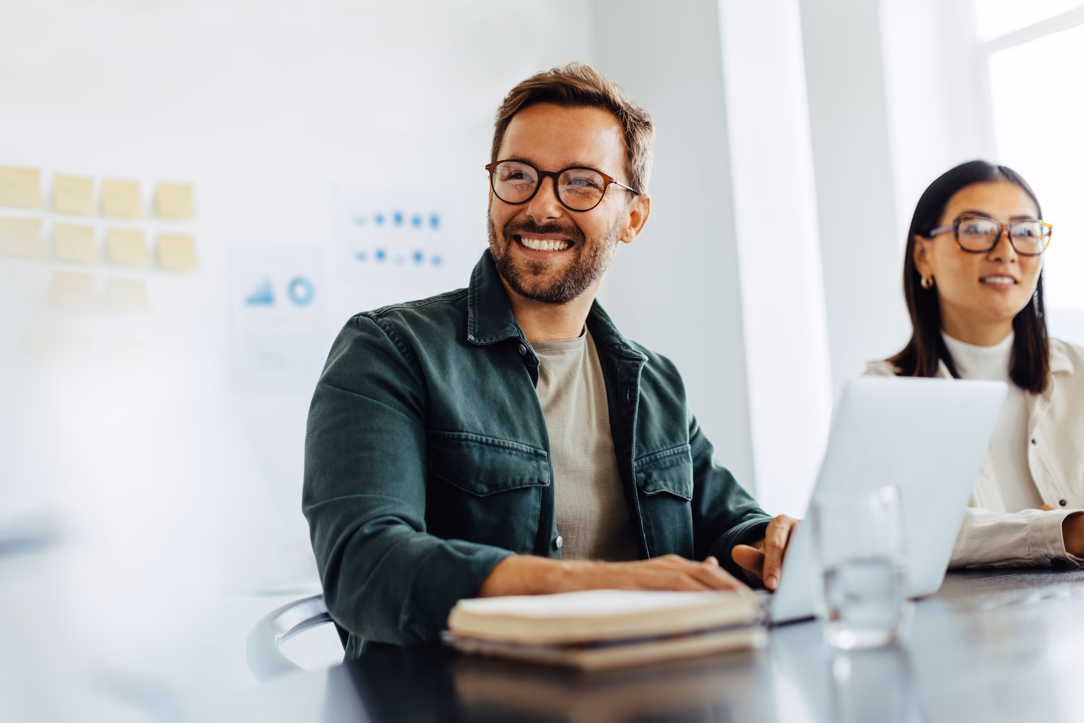 Happy businessman listening to a discussion in an office boardroom, symbolizing collaboration, professional engagement, and teamwork.